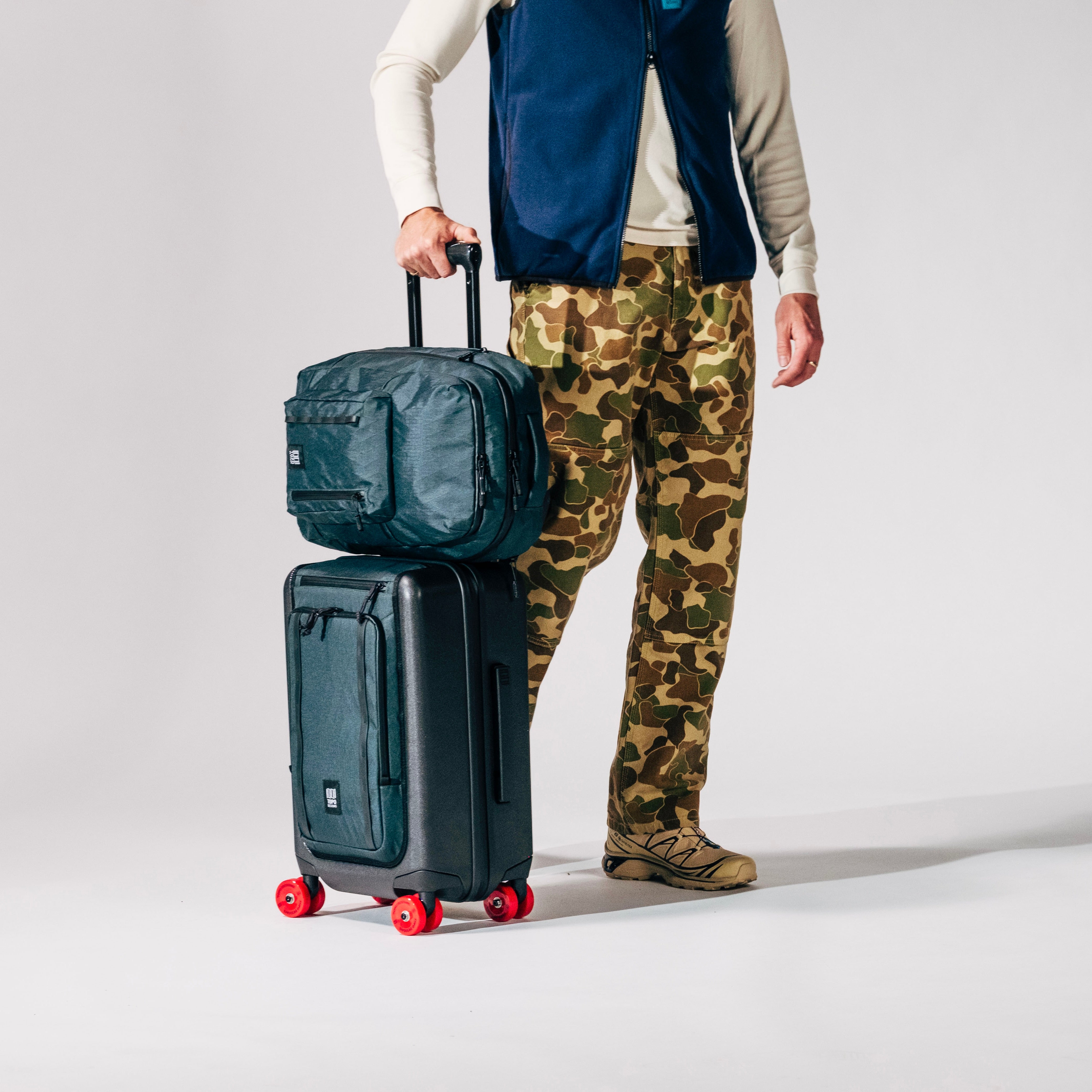 General shot of Topo Designs Global Pro Backpack shown in studio setting with system compatible roller bag