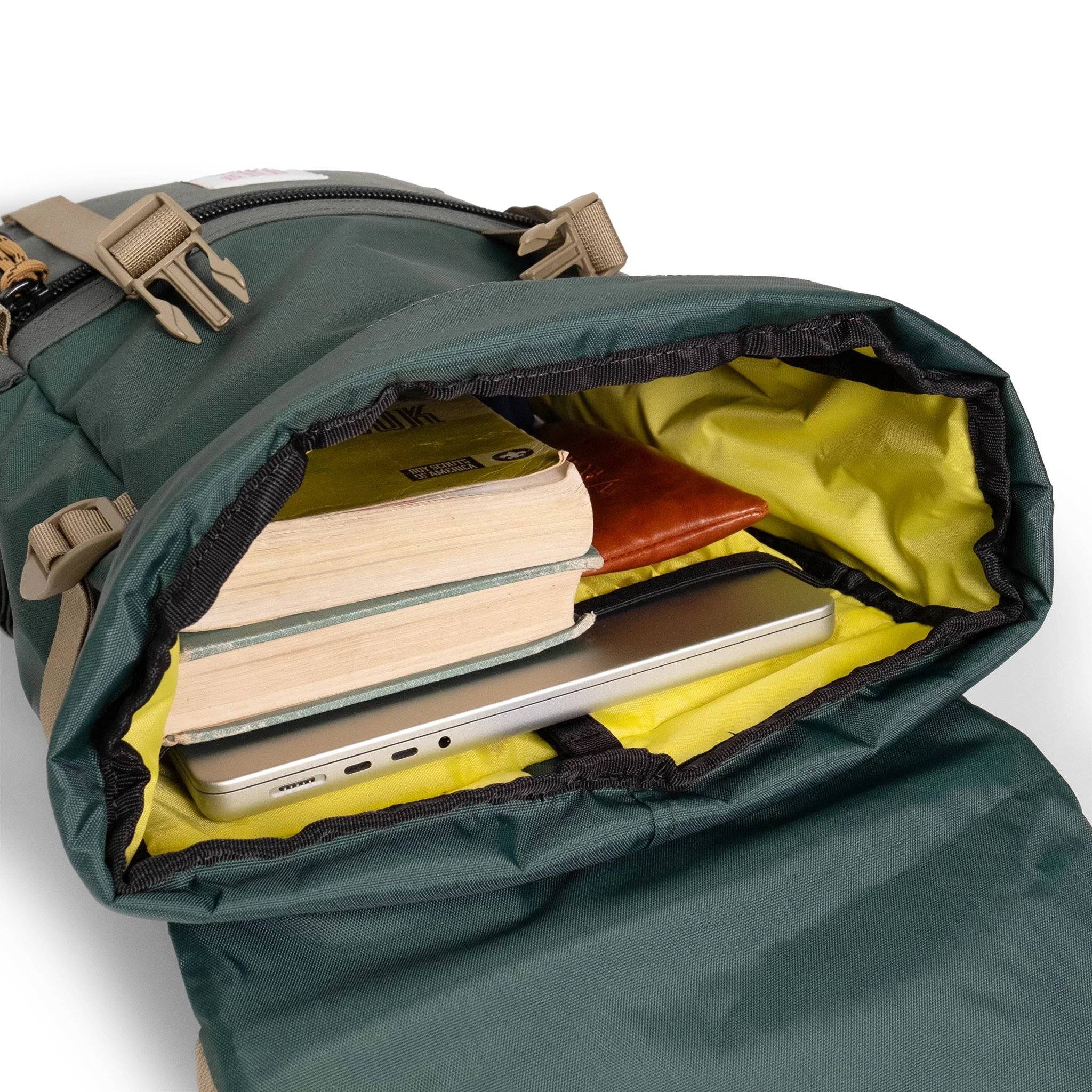 General shot Topo Designs Rover Pack Classic laptop backpack in "Forest" showing interior shot of backpack packed out with laptop, books, and glasses case.